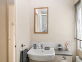 A bathroom with a sink mirror grey towel and toiletries at Ocean Pearl in Kingsbridge