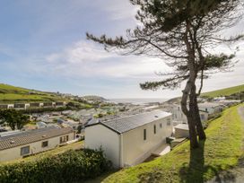 A view of a holiday park with multiple static caravans on grassy slopes near the coast at Ocean Pearl in Kingsbridge