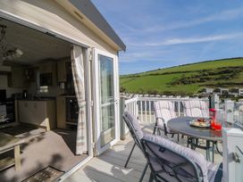 A balcony with a round table and four chairs overlooking green hills and a residential area at Ocean Pearl in Kingsbridge