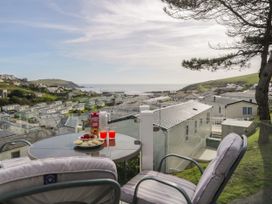 A balcony with a table set with juice glasses and snacks overlooking a caravan park and the sea at Ocean Pearl in Kingsbridge