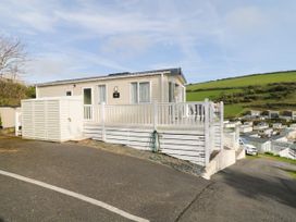 A mobile home with a white railing on a sloped road overlooking other mobile homes and green hills in the background at Ocean Pearl in Kingsbridge