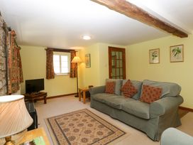 A living room with a sofa a rug a television and a lamp at Anvil Cottage in Gatcombe near Blakeney