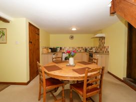 A kitchen with wooden table and four chairs with a flower vase in the center at Anvil Cottage Gatcombe near Blakeney