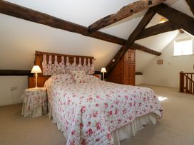 A bedroom with a bed with floral bedspread and wooden beams at Anvil Cottage in Gatcombe near Blakeney