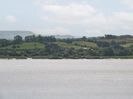 A landscape with hills, water, and boats at Anvil Cottage in Gatcombe near Blakeney
