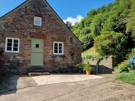 A cottage with a green door and flower planters at Anvil Cottage in Gatcombe near Blakeney