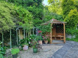 A garden with a gazebo and potted plants at Anvil Cottage in Gatcombe near Blakeney