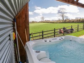An outdoor area with a hot tub and horses by the fence at Valley View Hideaway in Ffostrasol