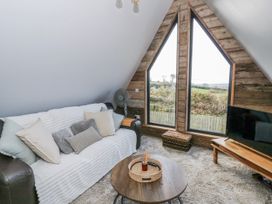 A living room with a sofa and large windows at Valley View Hideaway in Ffostrasol