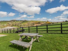 A picnic table in a field with cows and hills at Valley View Hideaway Ffostrasol