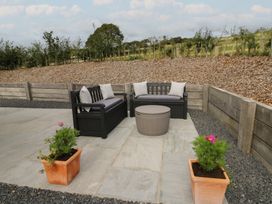 An outdoor seating area with a coffee table and flower pots at Rydlan Aberystwyth
