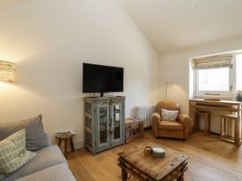 A living room with a television and seating area at The Little Loft in Burford