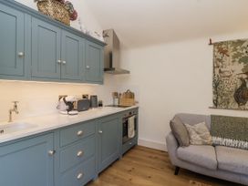 A kitchen with cabinets and a couch at The Little Loft in Burford