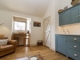 A living room with a window, table, chairs, and cabinets at The Little Loft in Burford