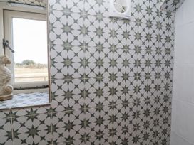 A bathroom with patterned tiles and a window at The Little Loft in Burford
