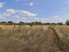 A path through grass and trees under a cloudy sky at The Little Loft in Burford
