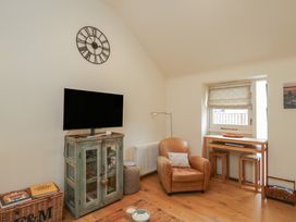 A living room with a television and a chair at The Little Loft in Burford