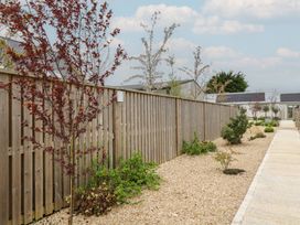 A garden with a wooden fence and gravel path at The Little Loft in Burford