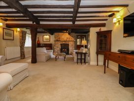 A living room with exposed wooden beams a stone fireplace two white sofas a piano and wooden furniture at New Hall in Chirk