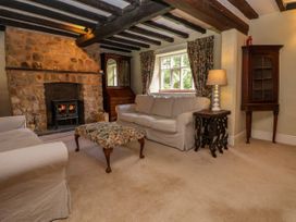 A living room with a stone fireplace wood stove sofas floral curtains and wooden furniture at New Hall in Chirk