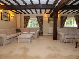 A living room with beige sofas a wooden beam ceiling and floral curtains at New Hall in Chirk