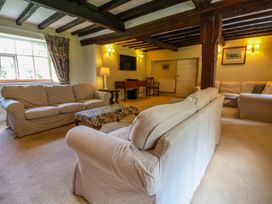 A living room with three sofas a floral ottoman wooden beams and wall mounted TV at New Hall in Chirk