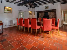 A dining room with a long wooden table and orange chairs on tiled floor at New Hall in Chirk