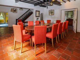 A dining room with a wooden table and red chairs on a tile floor at New Hall in Chirk