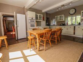 A kitchen with a wooden dining table and chairs near white cabinets and appliances at New Hall in Chirk