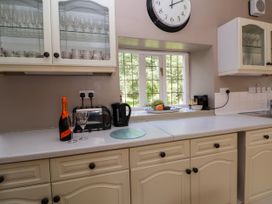 A kitchen countertop with a bottle of sparkling wine and two glasses next to a toaster and electric kettle under a wall clock at New Hall in Chirk