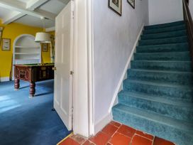 A staircase with blue carpet and a door leading to a room with a pool table and yellow walls at New Hall in Chirk