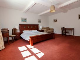 A bedroom with a double wooden bed two bedside tables with lamps a beige sofa a desk with a chair and a wooden chair at New Hall in Chirk