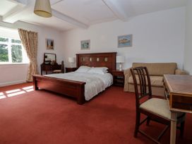 A bedroom with a wooden bed a desk chair sofa and dresser near a window at New Hall in Chirk