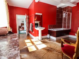 A bathroom with a bathtub shower combination sink and a chair with red upholstery at New Hall in Chirk