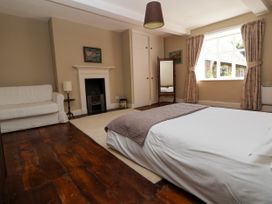 A bedroom with a bed a white sofa a fireplace a floor mirror and a window with curtains at New Hall in Chirk