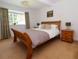 A bedroom with a wooden bed frame white bedding and two bedside tables each with a lamp at New Hall in Chirk