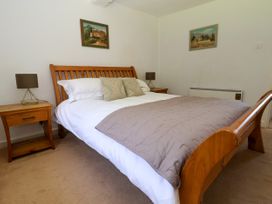 A bedroom with a wooden bed frame and bedside tables with lamps at New Hall in Chirk
