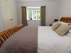 A bedroom with a wooden bed frame two pillows two rolled towels on the window sill and a bedside table with a lamp at New Hall in Chirk
