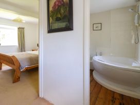 A bedroom with a wooden bed and a bathroom with a white bathtub at New Hall in Chirk