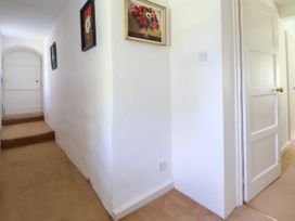 A hallway with three framed pictures on white walls and a closed white door at New Hall in Chirk