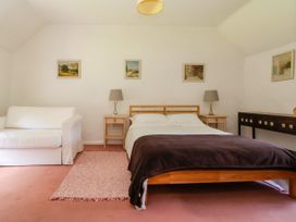 A bedroom with a wooden bed, two bedside tables with lamps, a white sofa, and framed pictures on the wall at New Hall in Chirk