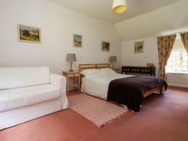 A bedroom with a bed sofa rugs lamps paintings and curtains at New Hall in Chirk
