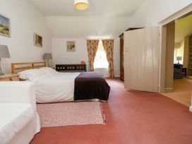 A bedroom with a bed white sofa rug and curtains at New Hall in Chirk
