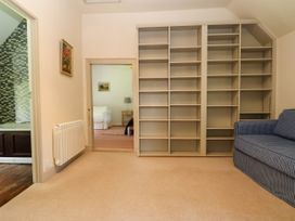 A room with empty wall shelves a blue checkered sofa and an open doorway showing another room with a white couch at New Hall in Chirk