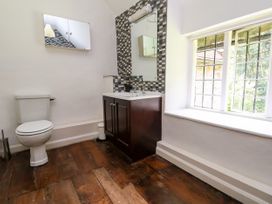 A bathroom with a toilet sink cabinet mirror window and wooden floor at New Hall in Chirk