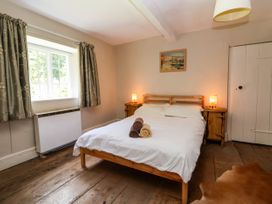 A bedroom with a wooden bed with white bedding and rolled towels bedside tables with lamps a window with curtains and wooden floor at New Hall in Chirk