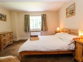 A bedroom with a wooden bed and white bedding two bedside tables with lamps a chest of drawers curtains on the window and artwork on the walls at New Hall in Chirk
