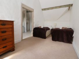 A bedroom with two single beds with brown blankets and rolled towels a wooden chest of drawers and an open door to a bathroom at New Hall in Chirk