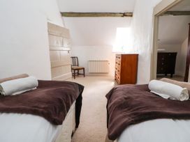 A bedroom with two single beds each with a rolled towel and dark blanket a wooden chair and chest of drawers at New Hall in Chirk