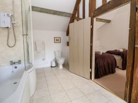 A bathroom with a bathtub shower combination toilet and towel rack next to a bedroom with two beds at New Hall in Chirk